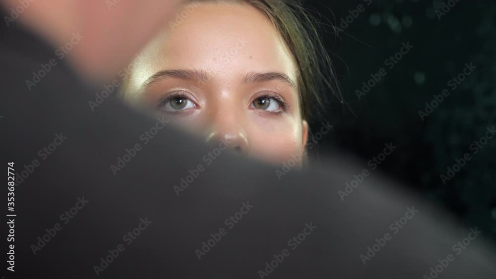 Professional makeup artist puts glitter on the face and eye of a teenager girl in a beauty salon. 4K slow motion footage