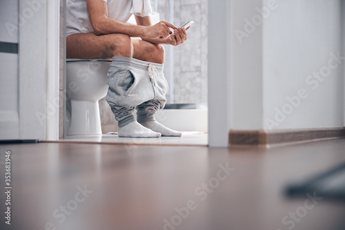 Man using his gadget in the water closet photo