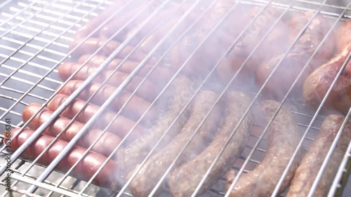 sausages and cevapcici fried meat grilled on an iron grate .