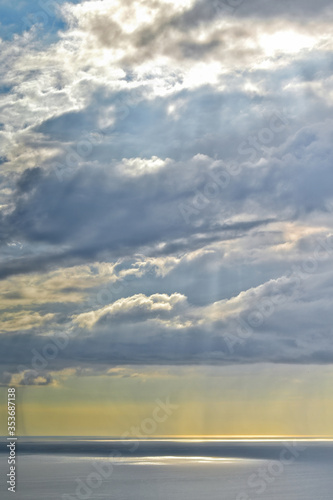 Sun shines through rain clouds over Tasman sea horizon