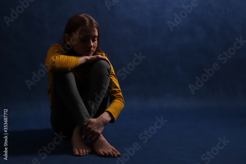 Teen girl sitting hugging his hands. Adolescent psychological and social problems. photo