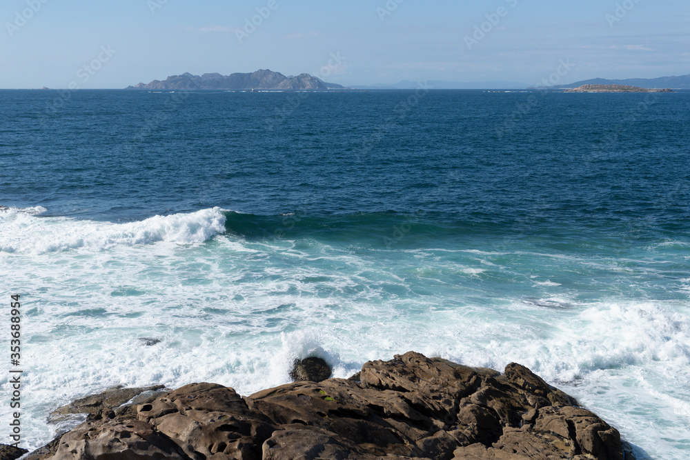 ocean wave splash on rocks on the coast on a sunny day with blue sky ocean wave splash on rocks on the coast on a sunny day with blue sky