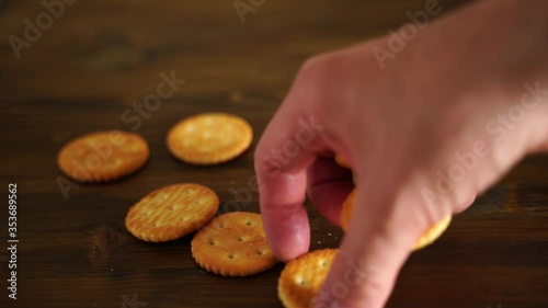 flour biscuit salted cracker rests on a wooden background. The human hand takes one