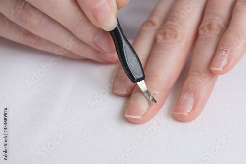 Home manicure. Self-treatment of nails during the pandemic and quarantine. Cuticle removal with a special tool. Close up.