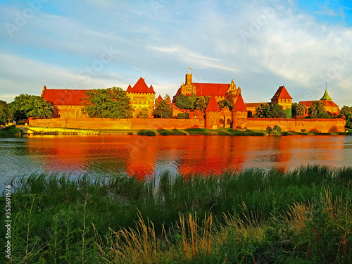 Mighty castle of the Teutonic Knights Order in Malbork (Poland, historical Prussia) on a dawn. The biggest brick gothic fortress in the world, UNESCO world heritage site. Fairy-tale medieval castle. 