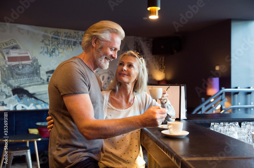 A couple standing together at a bar with cups of coffee. photo