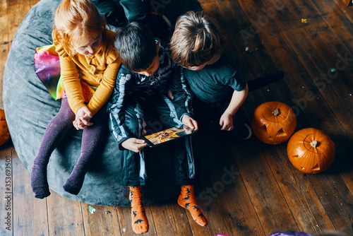 Three children sitting on a beanbag looking at a computer tablet.