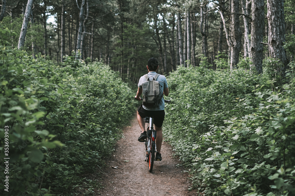 Young man with backpack cycling on a forest path, active lifestyle, playing sports in nature. Young man with backpack cycling on a forest path, active lifestyle, playing sports in nature.