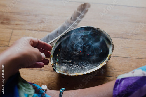 Woman burning sage to promote health, clarity and healing at home for relaxation photo