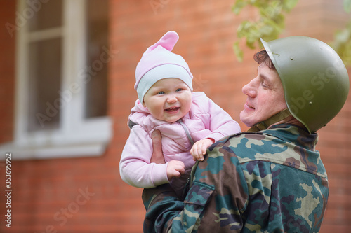 Tableau sur toile Military man in a helmet with a smiling little baby in his arms