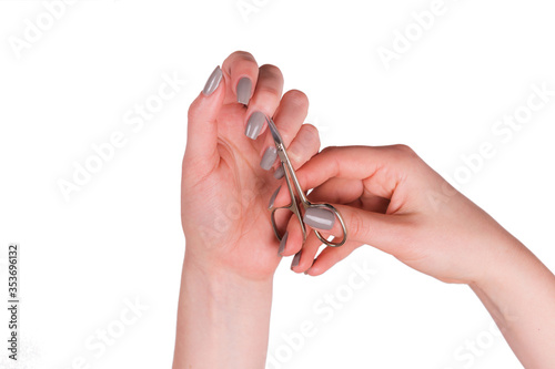 Female hands hold scissors for manicure and cut cuticles around the nail