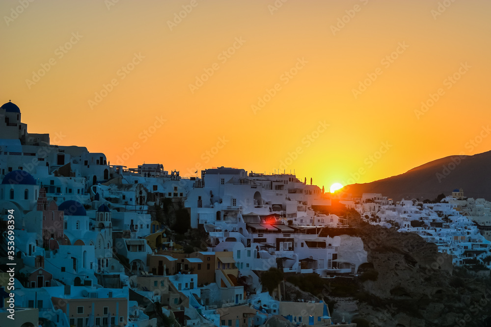 Sunrise in Oia, Santorini, Greece. Sun is rising behind the mountains above the traditional village of Oia in the Greek island of Santorini. 
