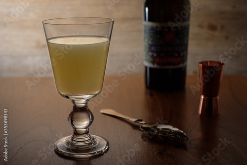 Glass with mint green absinthe on wooden table