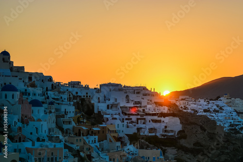 Sunrise in Oia, Santorini, Greece. Sun is rising behind the mountains above the traditional village of Oia in the Greek island of Santorini.  © Aalez