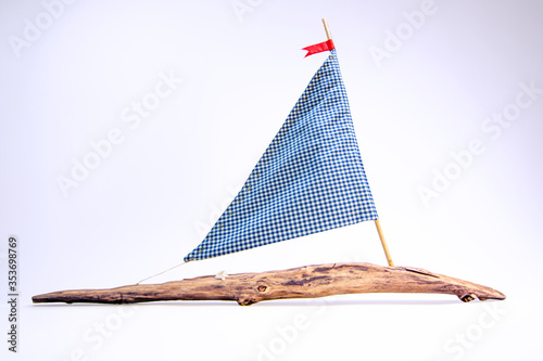 A sailboat isolated on a white background with checkered blue sail and wooden deck