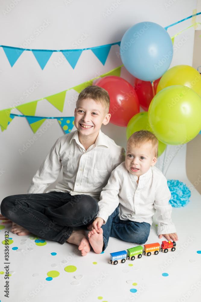 Fototapeta premium The brothers play with the train. the boy's birthday . decorations balloons and flags