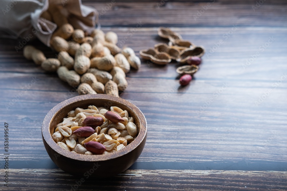 Peanuts in a wooden bowl on wooden table with peanuts in background. Healthy snack. Close up view. Peanuts in a wooden bowl on wooden table with peanuts in background. Healthy snack. Close up view.