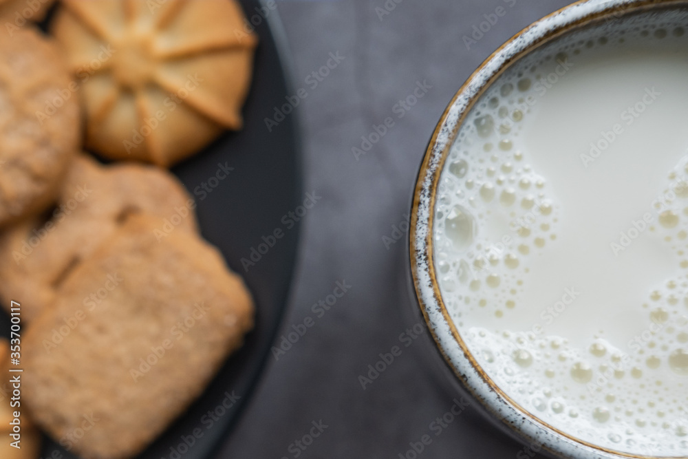 Milk cup and danish cookines in background. Close up view. Milk cup and danish cookines in background. Close up view.