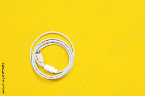 May 01, 2020, Rostov, Russia: White Apple wire lightning to usb type c, arranged in round skein on bright yellow background.