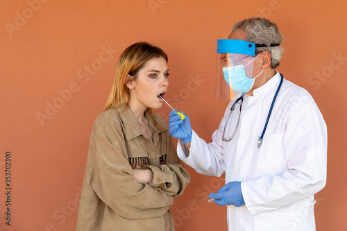 Covid-19 swab test. Search for coronavirus in a girl. Doctor takes a sample from the throat of a young woman, for subsequent laboratory analysis in search of the SARS-CoV-2 virus.