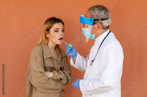 Covid-19 swab test. Search for coronavirus in a girl. Doctor takes a sample from the throat of a young woman, for subsequent laboratory analysis in search of the SARS-CoV-2 virus.