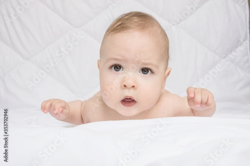 Sweet little baby boy sitting on his tummy, white background