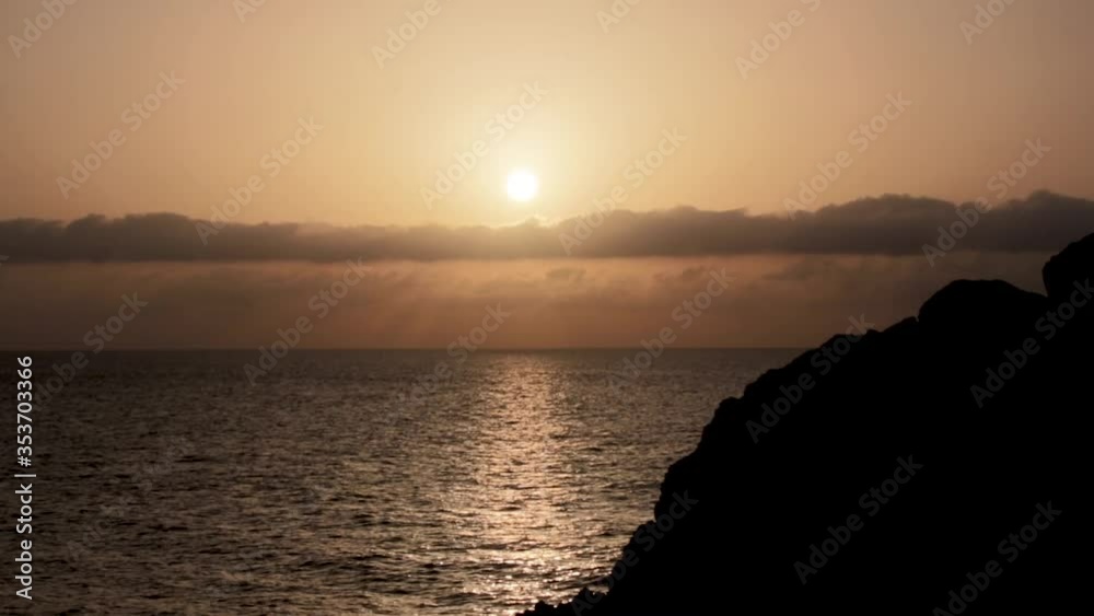 Sunset in the ocean in calm with lineal clouds in the horizont and a big rock and seagulls Sunset in the ocean in calm with lineal clouds in the horizont and a big rock and seagulls