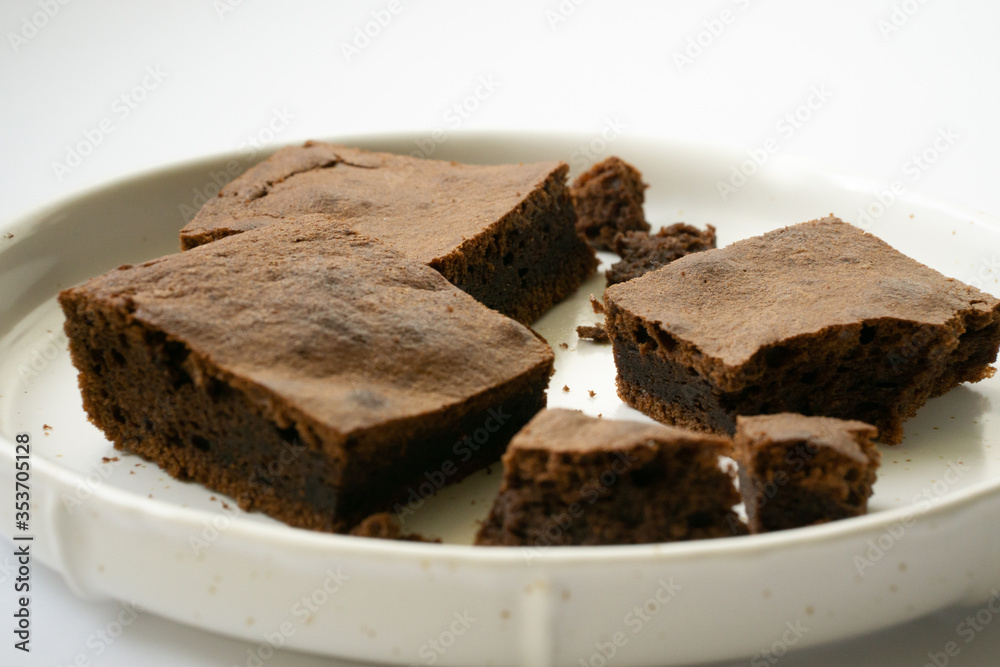 Chocolate brownie sliced into square slices on a white plate. Chocolate brownie sliced into square slices on a white plate.