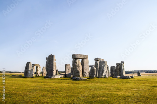 Standing rocks of ancient Stonehenge with defining shadows under clear blue sky on bright summer morning standing alone on Salisbury Plain