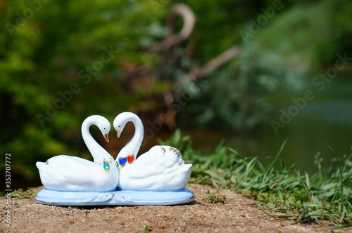 Fototapeta Naklejka Na Ścianę i Meble -  A pair of souvenir swans in wild flowers. A symbol of love and happy family life.