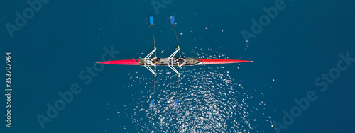 Aerial drone top ultra wide panoramic view of sport canoe rowing synchronous female athletes competing in deep blue sea
