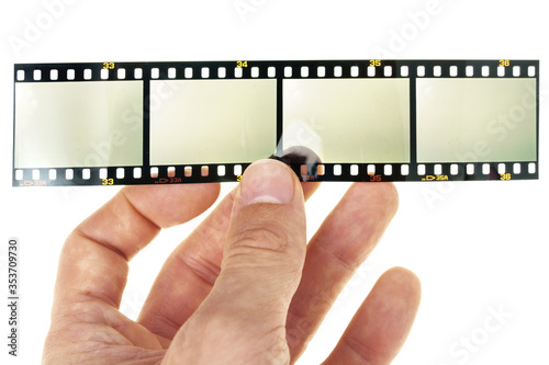 male hand is holding long 35mm filmstrip with 4 empty or blank film cells or frames on white background, exposed film material, blend in your photos to let them look old and vintage.