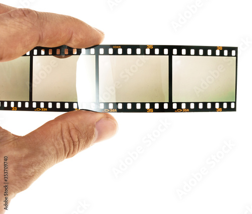 male hand is holding long 35mm filmstrip with 4 empty or blank film cells or frames on white background, exposed film material, blend in your photos to let them look old and vintage.