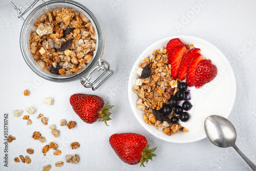  Bowl of homemade granola with yogurt and fresh berries on white background from top view