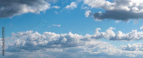 Panorama of blue sky with white curly clouds
