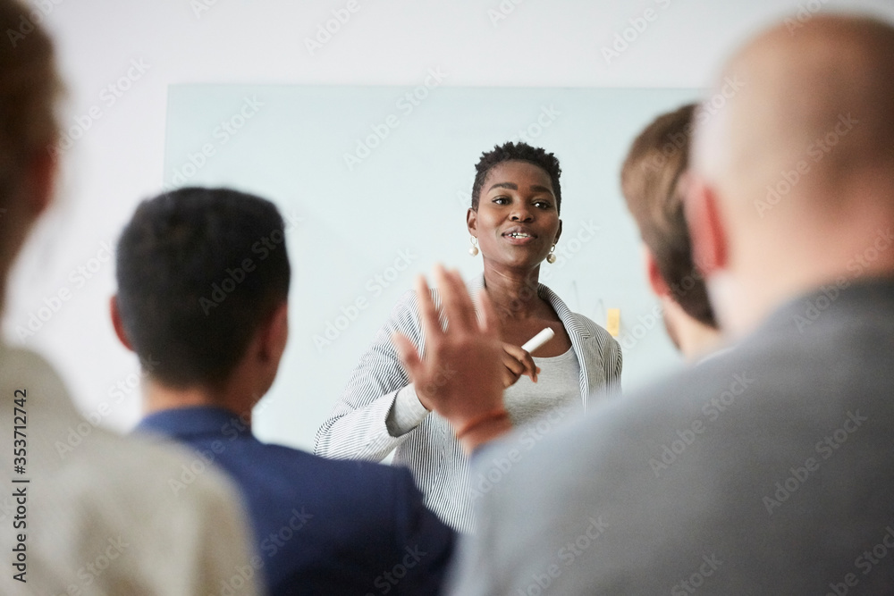 Smiling businesswoman talking with colleagues during presentation while standing in office seminar Smiling businesswoman talking with colleagues during presentation while standing in office seminar