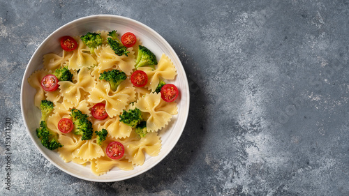 Farfalle pasta bow tie with broccoli and cherry tomatoes. Top view. Flat lay photo.