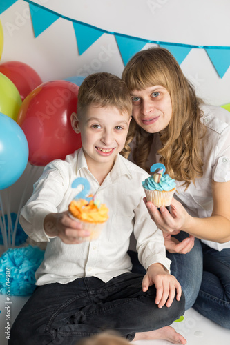 mother with son holding a cupcake with the number two