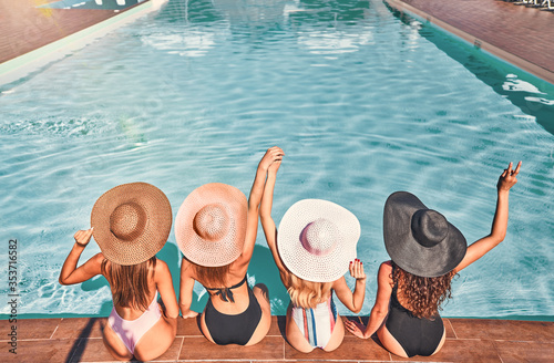 Cuadro en lienzo Four beautiful young woman sitting by the poolside