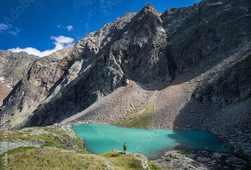 Man standing at turquoise lake Vordersee in Gradental national park Hohe Tauern with mountain in the background, Austria.