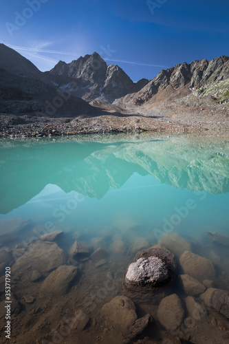 Turquoise lake Gradensee at Nossberger Hut, mountains and reflection on water surface, in Gradental in national park Hohe Tauern, Austria. photo