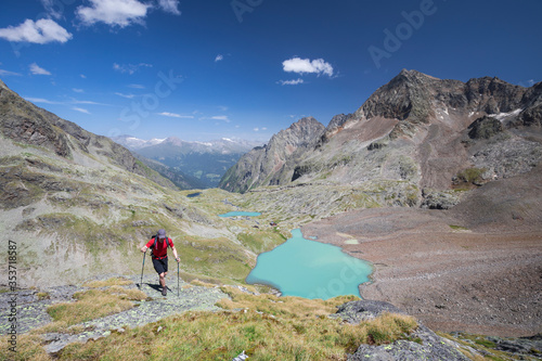 Hiking person at turquoise lake Gradensee at Nossberger Hut, mountains and valley, in Gradental in national park Hohe Tauern, Austria. photo