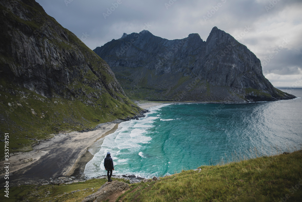 Man standing on rock by Kvalvika Beach in Lofoten Islands, Norway Man standing on rock by Kvalvika Beach in Lofoten Islands, Norway