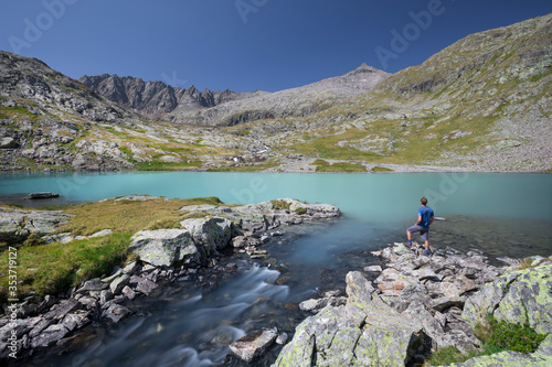 Hiking person at turquoise lake Mittersee at Nossberger Hut, mountains and valley, in Gradental in national park Hohe Tauern, Austria. photo