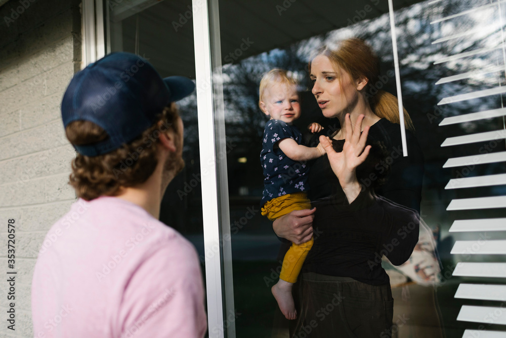 Mother with daughter (2-3) talking to man through window Mother with daughter (2-3) talking to man through window