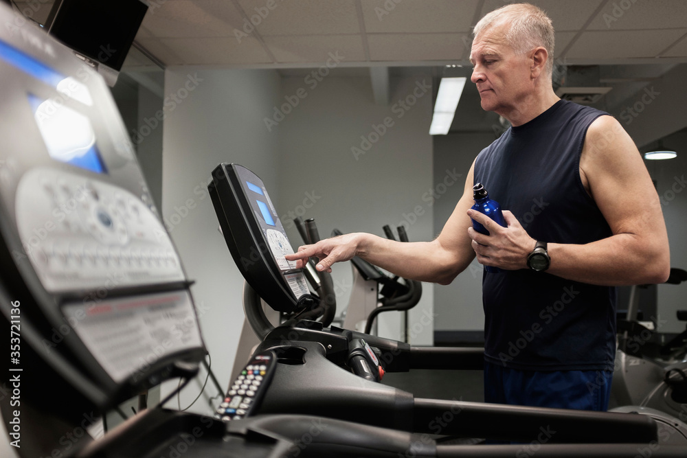 Man in health club adjusting treadmill before training Man in health club adjusting treadmill before training