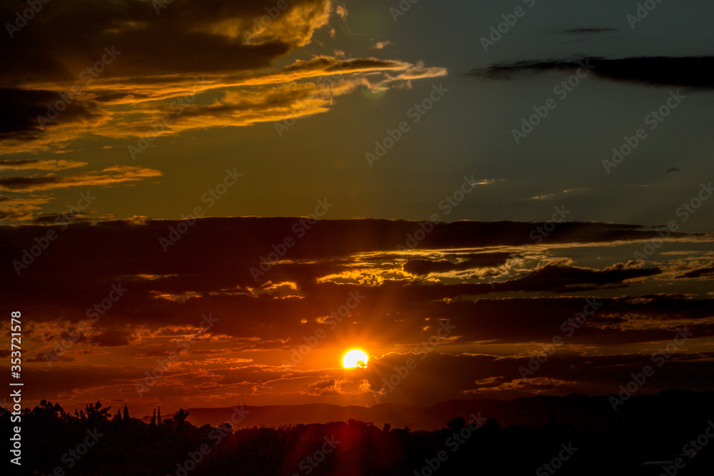 Beautiful close-up of Golden Sunset over the horizon, rich in color with a red, yellow and golden haze, scattered clouds, mountains and trees. Beautiful close-up of Golden Sunset over the horizon, rich in color with a red, yellow and golden haze, scattered clouds, mountains and trees.