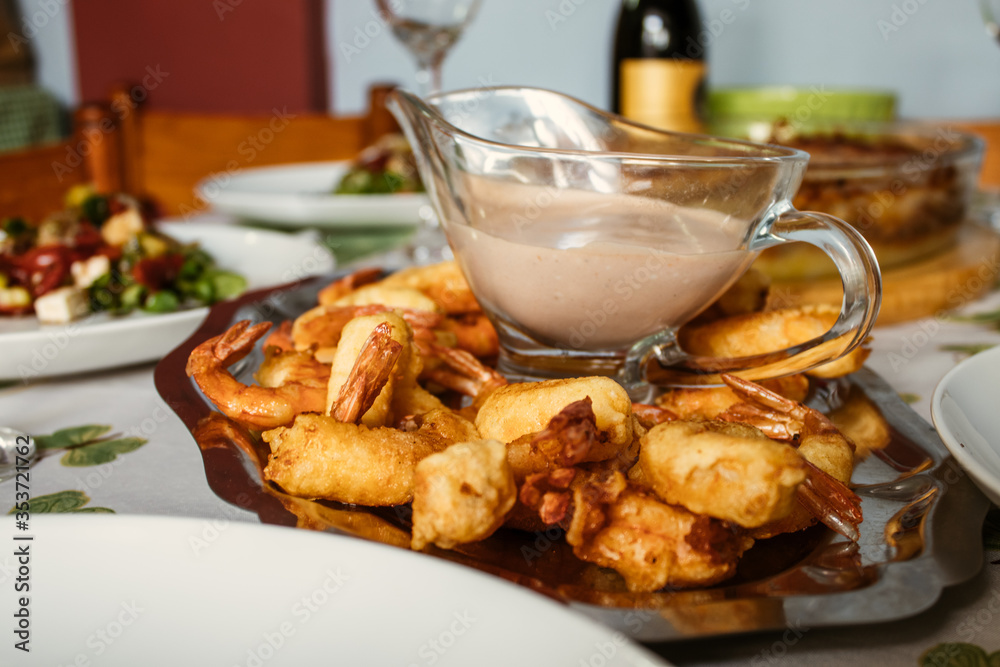 Plate of fried prawns with sauce. In the background you can see a bottle of wine. Plate of fried prawns with sauce. In the background you can see a bottle of wine.