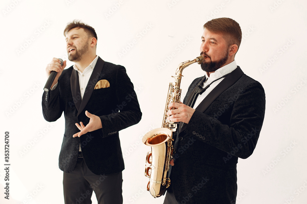Fototapeta premium Man with a microphone. Singer in studio. Musician with saxophone. Music band.
