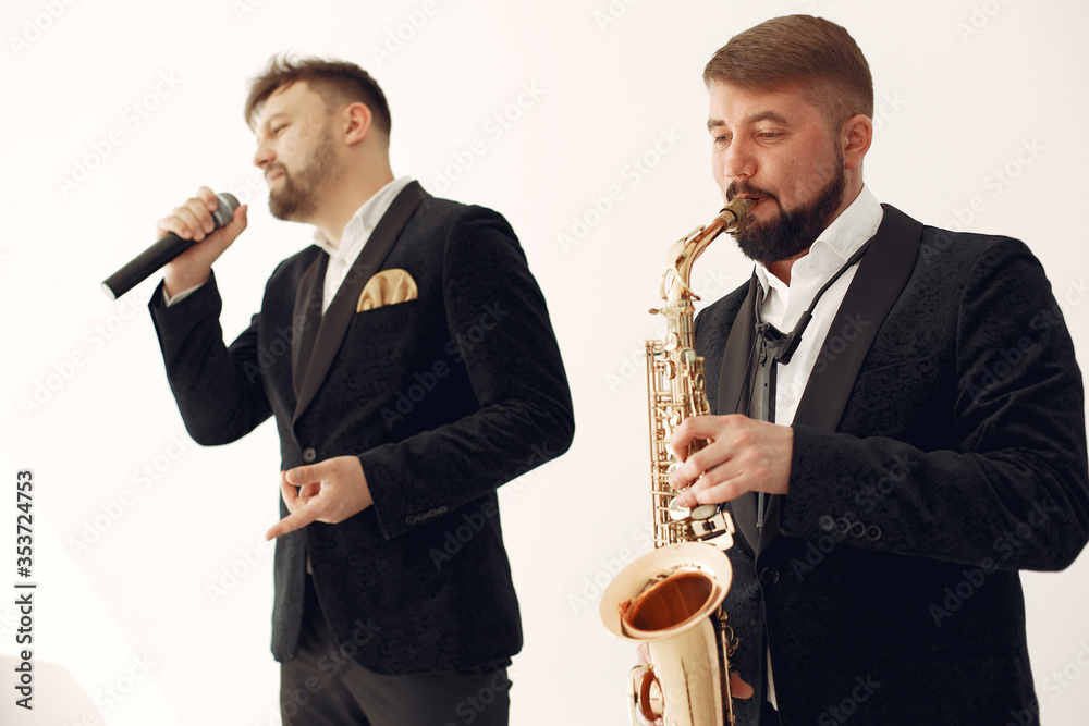 Fototapeta premium Man with a microphone. Singer in studio. Musician with saxophone. Music band.